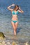 Girl in bikini stands in water laughing looking down