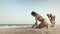Girl in a bikini swimsuit with dark hair draws on the beach with shells near the sea