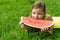 Girl bites a big tasty slice of watermelon, lies on green grass