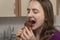 Girl is biting chocolate cake. Young woman tastes eclair with chocolate icing