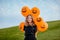 Girl in black clothes holding bunch of halloween balloons on a hill. Copy space