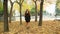 Girl in a black coat with rufous hair walking along autumn park.