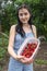 A girl with black hair smiles and holds a ripe strawberry in her hands. Harvest strawberries.