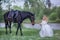 Girl with black horse in blossom garden