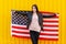 A girl in a black jacket with an open American flag