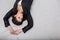 Girl in black leather jacket lying on a white parquet floor background with her hands on the floor over head