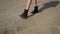A girl in black leather shoes walks along the beach and kicks the sand.