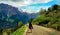 A girl in a black long coat and a red crossbody bag walking along the path to the Himalayan mountains.