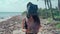 Girl with a black plastic bag on her head and a dead corral in her hands on a Caribbean beach with seaweed and garbage