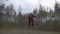 A girl in a black and red dress with an owl on her arm walks barefoot among a coniferous forest, slow motion shooting