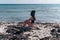 Girl in a black swimsuit with a plastic bag on her head and with a dead corral on a littered beach