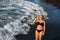 A girl in a black swimsuit walks on the beach on the island of Tenerife in the Atlantic Ocean, Spain