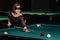A girl with a blindfold and a cue in her hands in a billiard club.Russian billiards