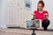 A girl blogger takes a fitness training lesson in front of a phone camera in a home kitchen. Playing sports at home in quarantine