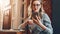 Girl blogger in trendy glasses sits in cafe and uses smartphone,checks e-mail,communicates with followers,reads news.