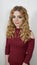 Girl is blonde with curly hair in a dark cherry turtleneck.