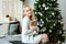 Girl the blonde in a light cozy sweater opens Christmas gifts