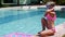 Girl blonde puts on goggles for swimming while sitting by the pool