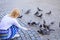 Girl blonde woman relaxing city square and feeding pigeons. Girl feeding dove birds. Group doves on city square waiting