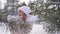 Girl blow snow from palms throw snow up and turn around in forest winter snowfall, show thumbs up