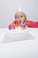 Girl blowing candles on birthday cake at table in house