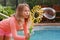 Girl blowing a large soap bubble outside by a swimming pool