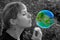 Girl blowing a soap bubble in the shape of a planet. Planet Earth. Earth. Conceptual image. Ecological concept