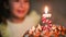 The girl blows out a burning candle with the number 5 on the cake and makes a wish. Birthday, fifth anniversary, five years, candl