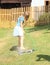 Girl in blue clothes washing foot on sprinkler