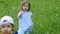 Girl in a blue dress blows on a dandelion while standing in a field