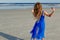 Girl in a blue dress dancing on the beach in front of the ocean