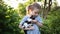 Girl in blue dress in garden in summer. child holds kitten in his arms outdoors. kid takes care of Pets.