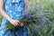 Girl in blue dress in her hands keeps bouquet of cornflowers in wheat field background