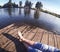 Girl in blue jeans sits on the old wharf in the lake