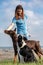A girl in a blue T-shirt stands on a hill and feeds her Doberman Dobermann and a border collie dogs with treats on a