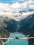 Girl in blue tshirt and a yellow hat sitting on a suspension bridge above the Alps. Freedom and adventure concept. Touristic