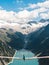 Girl in blue tshirt and a yellow hat sitting on a suspension bridge above the Alps. Freedom and adventure concept. Touristic