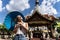 Girl with a blue umbrella in her hands with a comfortable expression sunbathing in front of a Buddhist temple