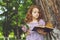 Girl with a book and a bouquet of lilacs near a large tree.