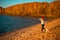 Girl with border collie dog on beach at seaside. autumn yellow forest on background