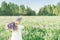 A girl with a bouquet of flowers over her shoulder in a white dress and a flower wreath walks back along the flower