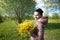 Girl with a bouquet of yellow rape. In the spring meadow. The sun shines brightly