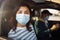 A girl and a boy driving in a car during coronavirus quarantine wearing medical masks. Safe taxi and healthcare during pandemic