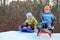 Girl and boy intend drive from hill on sledges