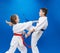 Girl and boy in karategi train the punch arm and kick leg