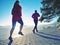 Girl and boy running while sun makes reflections in frozen lake surface.