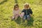 Girl and boy sit on green grass