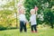 Girl and boy smiling laughing holding hands and waving American and Canadian flags, outside in park