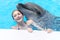 Girl with braces smiling and playing with dolphin in pool