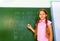 Girl with braids and chalk in hand near blackboard